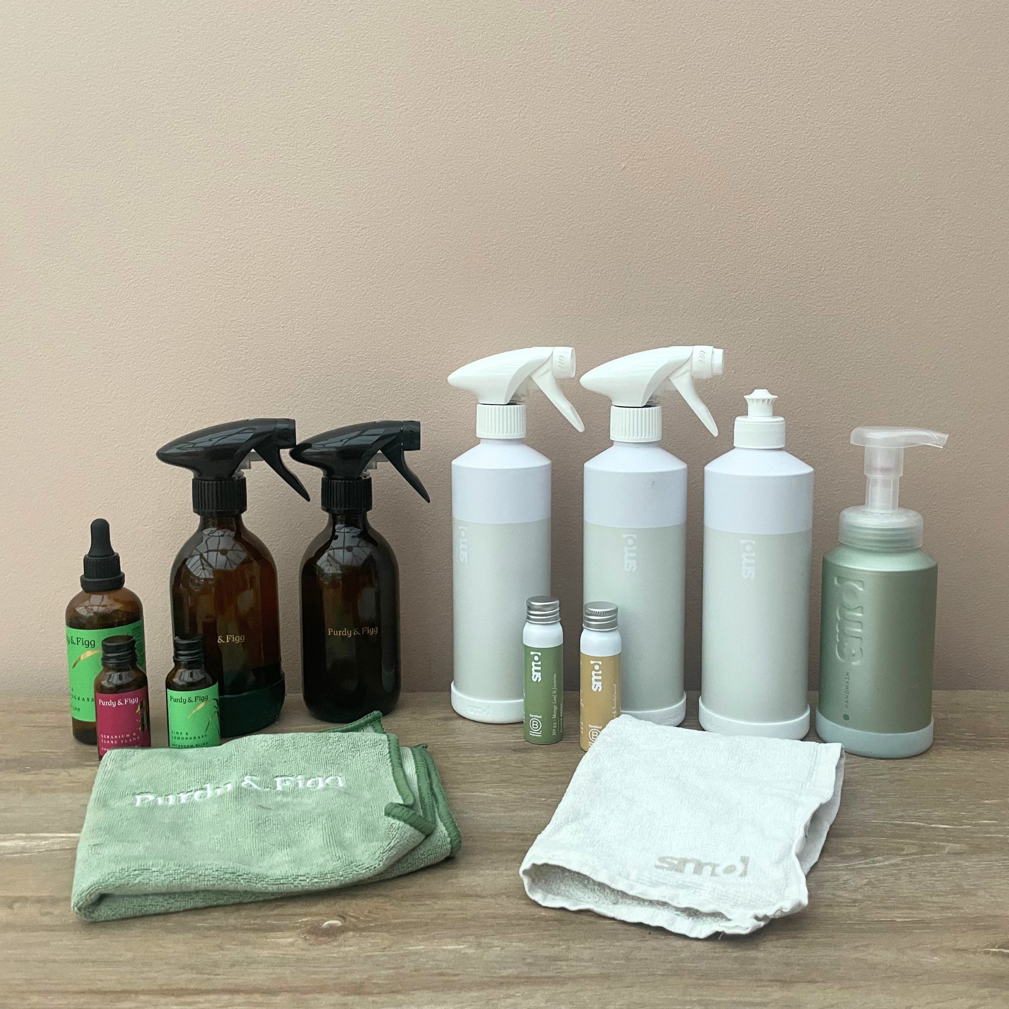 Purdy &amp; Figg and Smol cleaning products in a line in front of a plaster pink wall