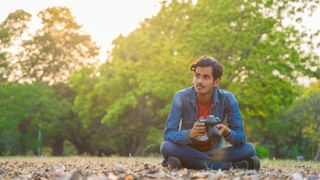 Man sitting outdoors holding the best camera for beginners