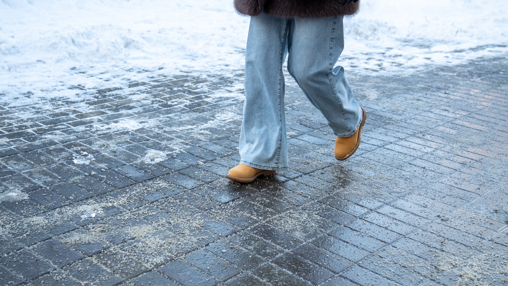 woman walking down salt covered snowy sidewalk