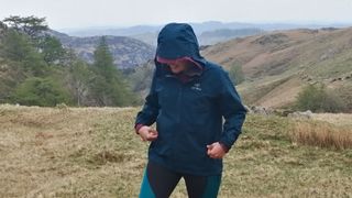 Woman wearing Arc'teryx Beta jacket on a mountainside, in the rain