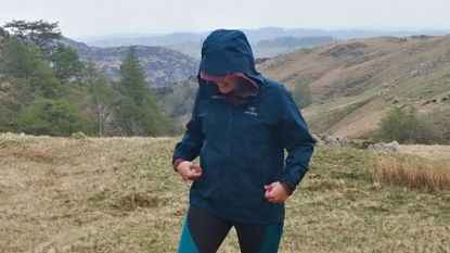 Waterproof vs water-resistant jackets: Woman wearing Arc'teryx Beta jacket on a mountainside, in the rain