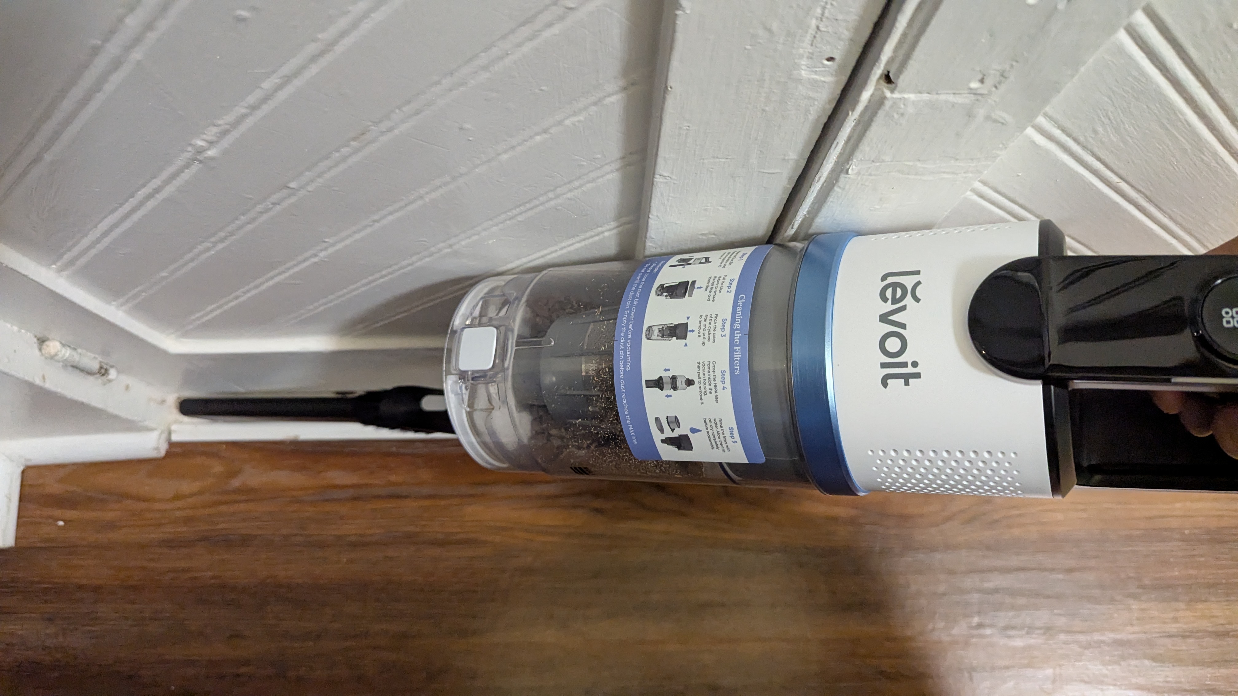Levoit Aero vacuum in handheld mode being used to clean baseboards