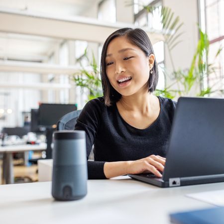 Young professional talking to virtual assistant at her desk.