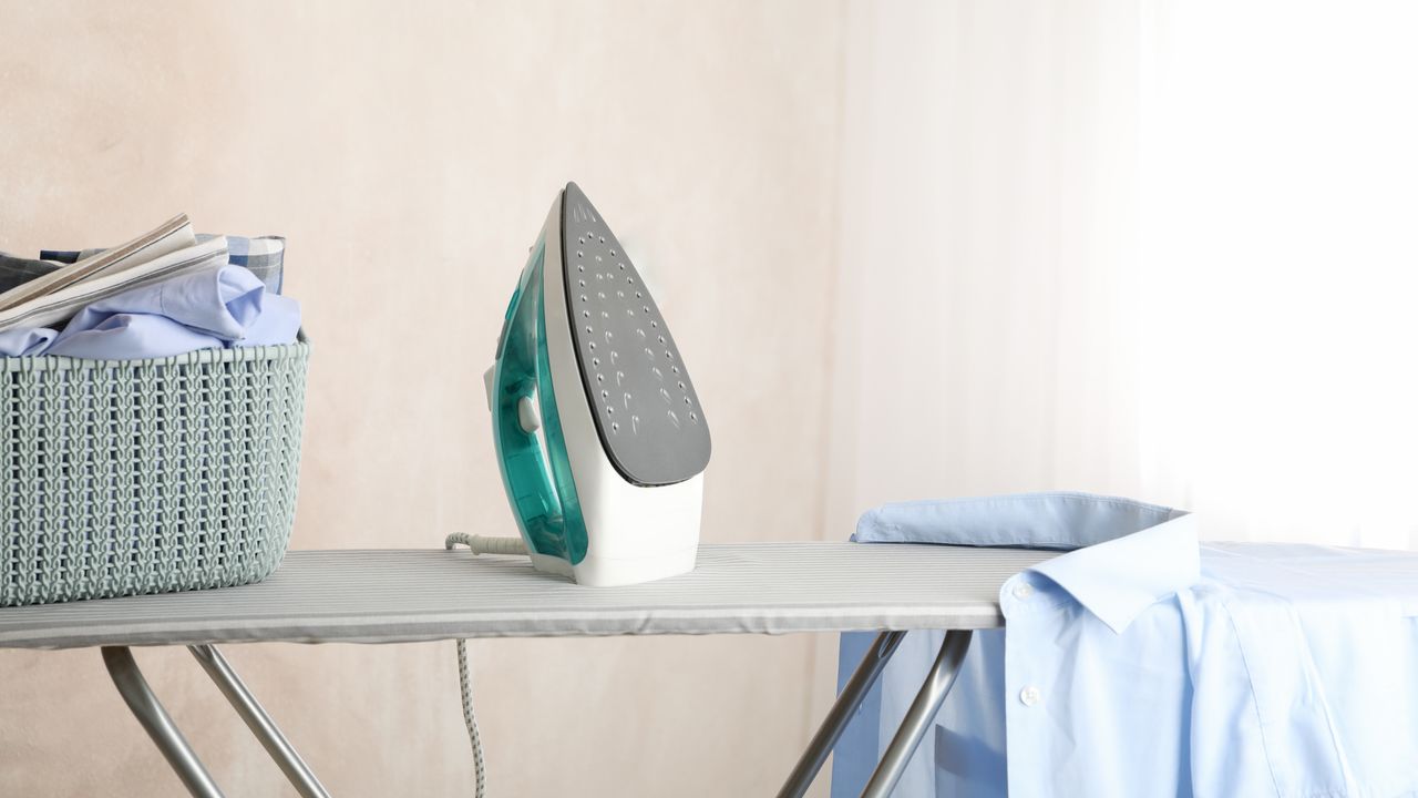 Steam iron on ironing board with folded clothes