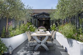 dining space surrounded by raised beds with a shed at the end of the garden