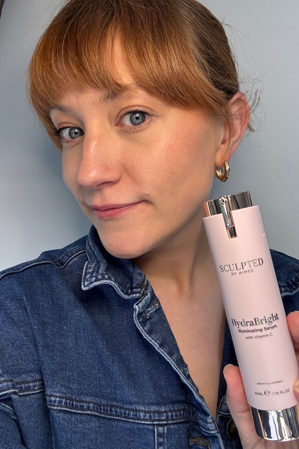 a headshot of matilda with a tube of sculpted by aimee serum