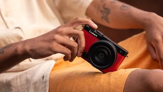 Panasonic Lumix S9 camera in red held in hand balanced on a person's leg