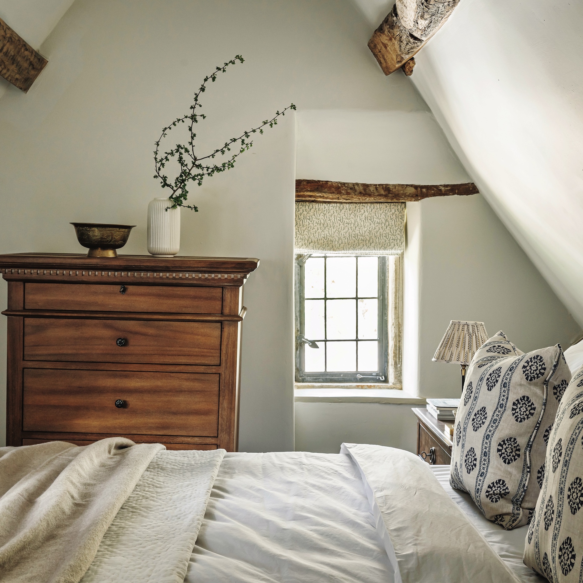 bed and chest of drawers in cottage bedroom with small window