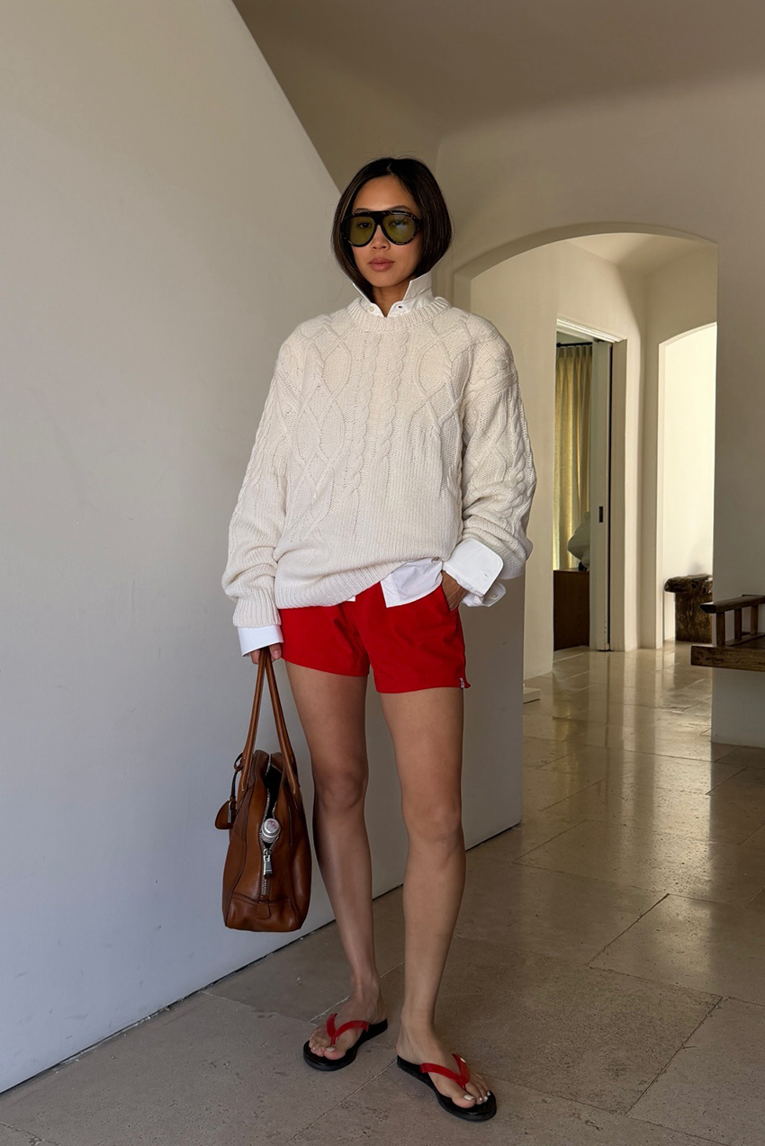 a woman wearing a beige jacket, red shorts, and red strap flip flops