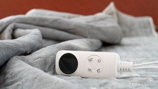 an electric blanket with a remote and a red wall in the background