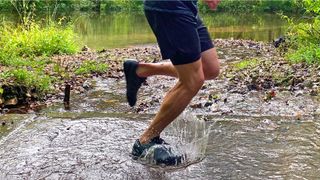 Man running through water in Xero Mesa Trail WP lightweight running shoes