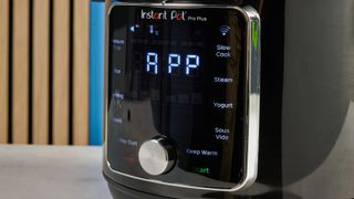 a black smart home enabled wi-Fi instant pot with a touchscreen and a 6QT inner pot is photographed against a blue background