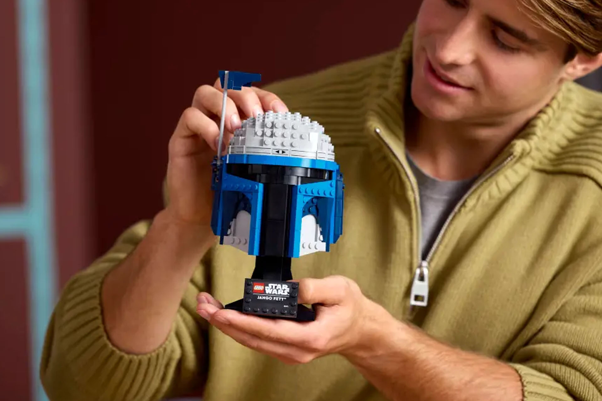 A Lego Star Wars Jango Fett Helmet being held in a person&#039;s hands.
