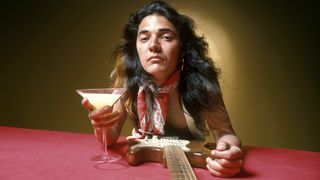  Tommy Bolin, posed, studio, with guitar and drink in cocktail glass, June 1975