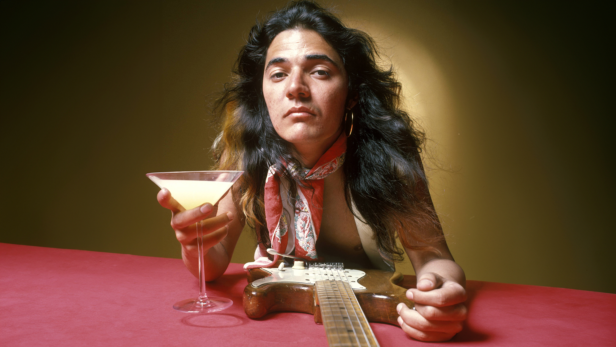  Tommy Bolin, posed, studio, with guitar and drink in cocktail glass, June 1975