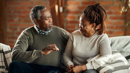 Smiling mature couple talking and relaxing on sofa in the living room