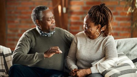 Smiling mature couple talking and relaxing on sofa in the living room