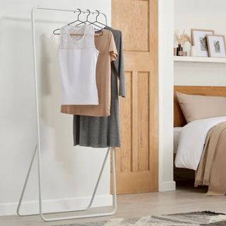 White clothes rail with hanging garments in bedroom