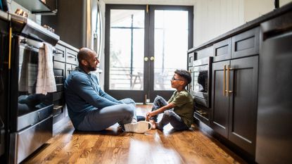 Father talking with his son while sitting on the kitchen floor