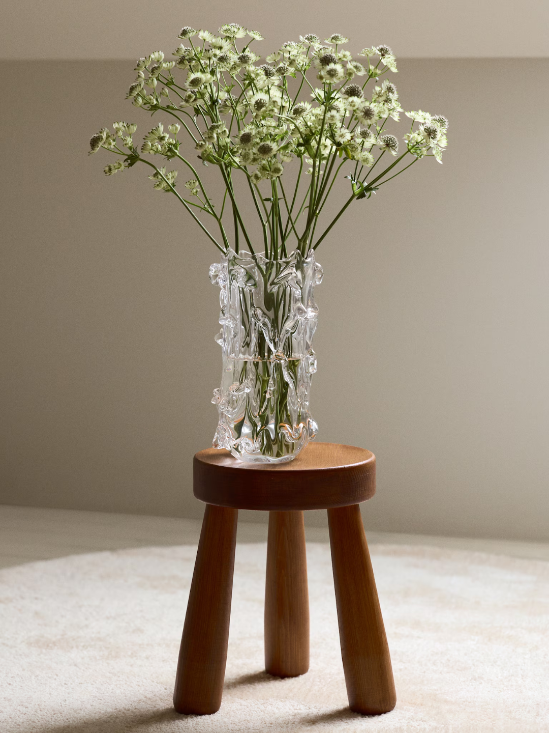 A textured glass vase on a stool