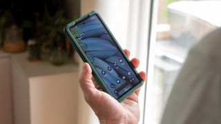 Looking at the home screen of the Google Pixel 7a that's in a green Otterbox Commuter case
