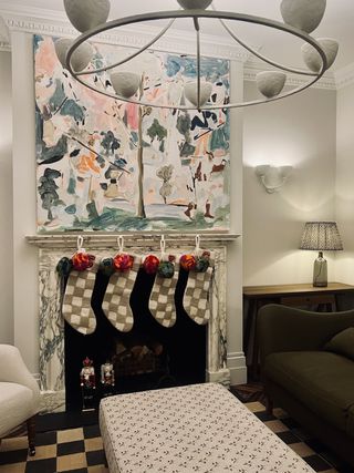 a marble fireplace decorated with stockings for christmas underneath colorful artwork