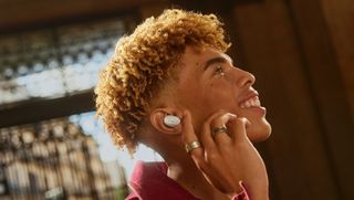 En person använder ett par vita Sennheiser Accentum-earbuds.