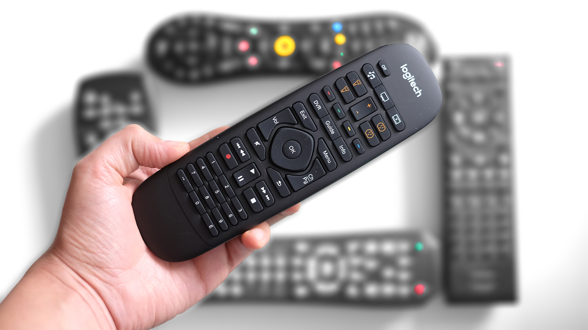 Five different remotes and a hand holding one above the others