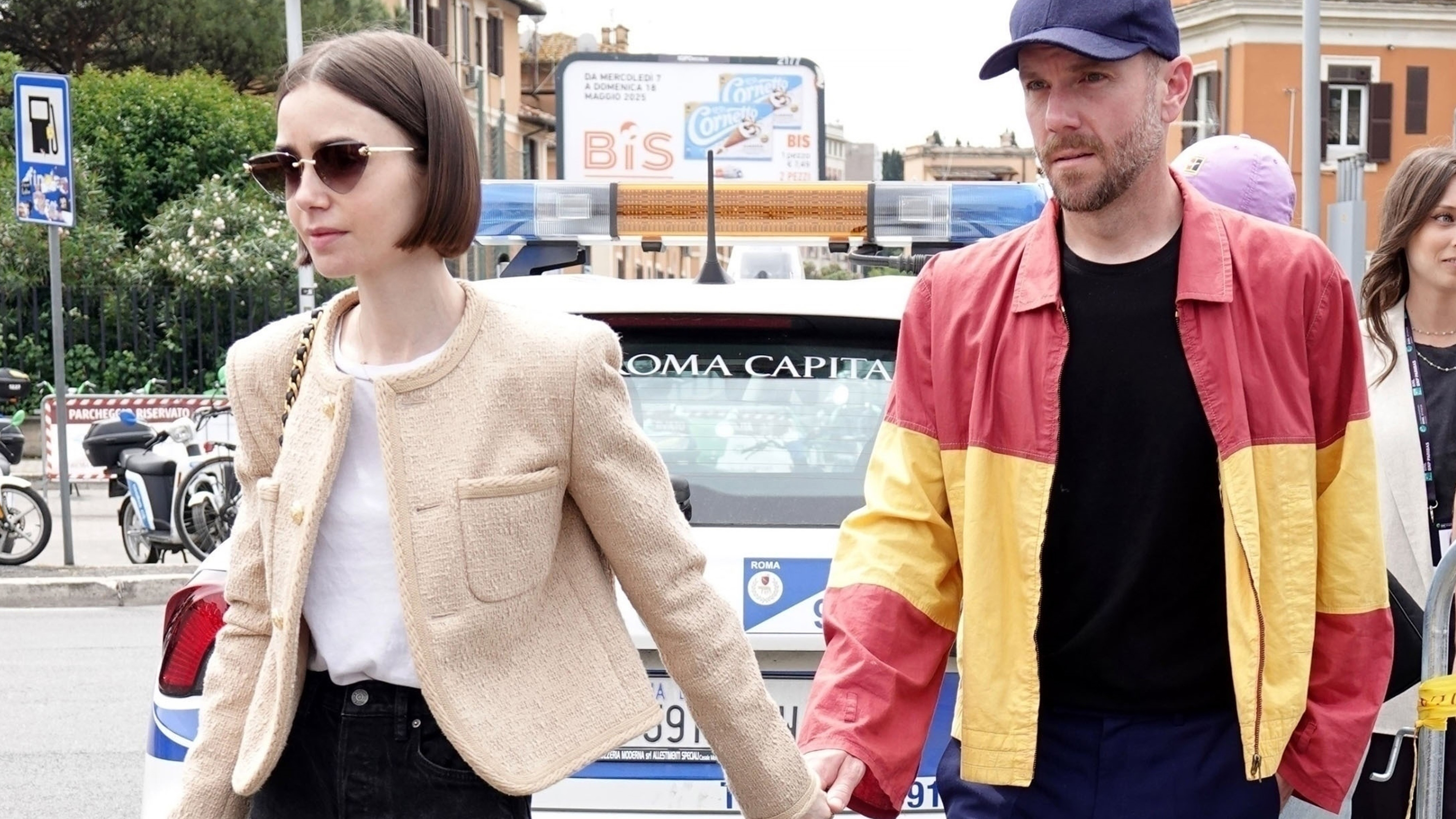 Lily Collins with her husband Charlie McDowell attending the Italian Open in Rome wearing a tan jacket and black Chanel bag with black jeans and Celine sandals.
