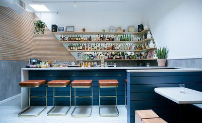 Blue bar front with leather-covered stools and bottles on wooden shelving