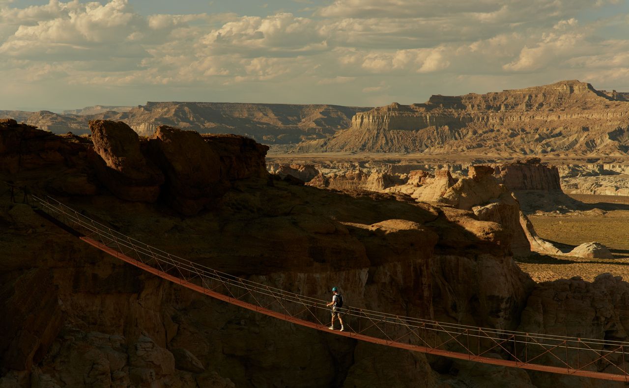 A man completes a ferrata between two canyons blessed by sunlight.