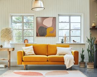 A mustard yellow velvet sofa in a light-filled open-plan living space