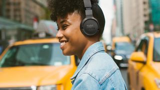 Woman wearing JBL 670NC headphones crossing street.