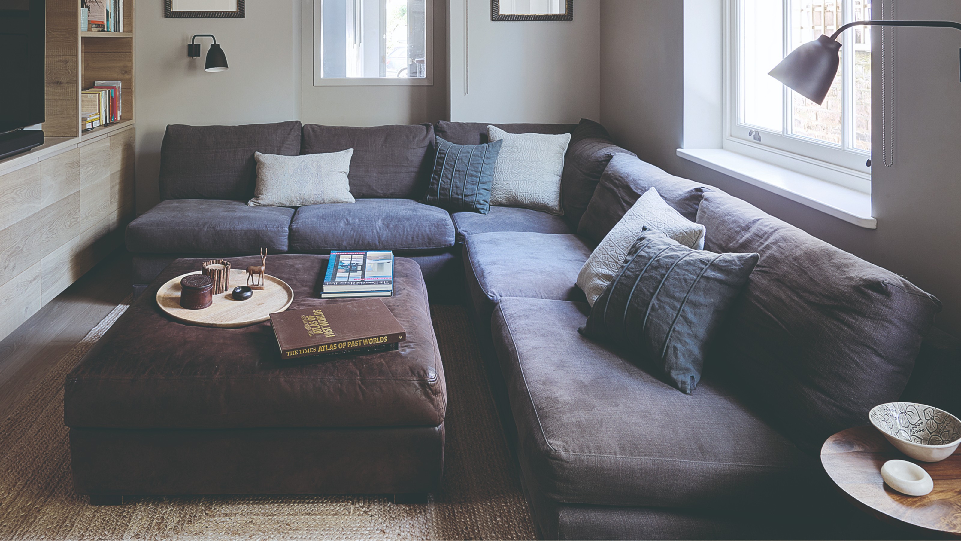 A cinema room with a large corner sofa with deep seats and a matching ottoman used as a coffee table