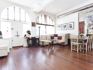 A studio living space with white walls, high ceilings, and arched windows