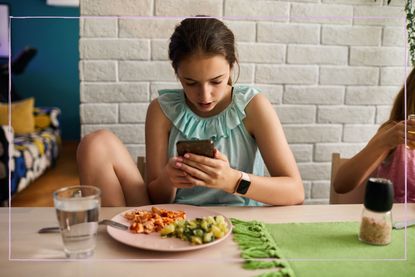 Teenage girl using smart phone for video game or social media while having lunch. Gaming disorder concept.