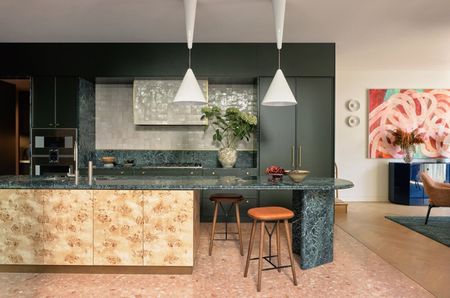 a green kitchen with a burled cabinet base island