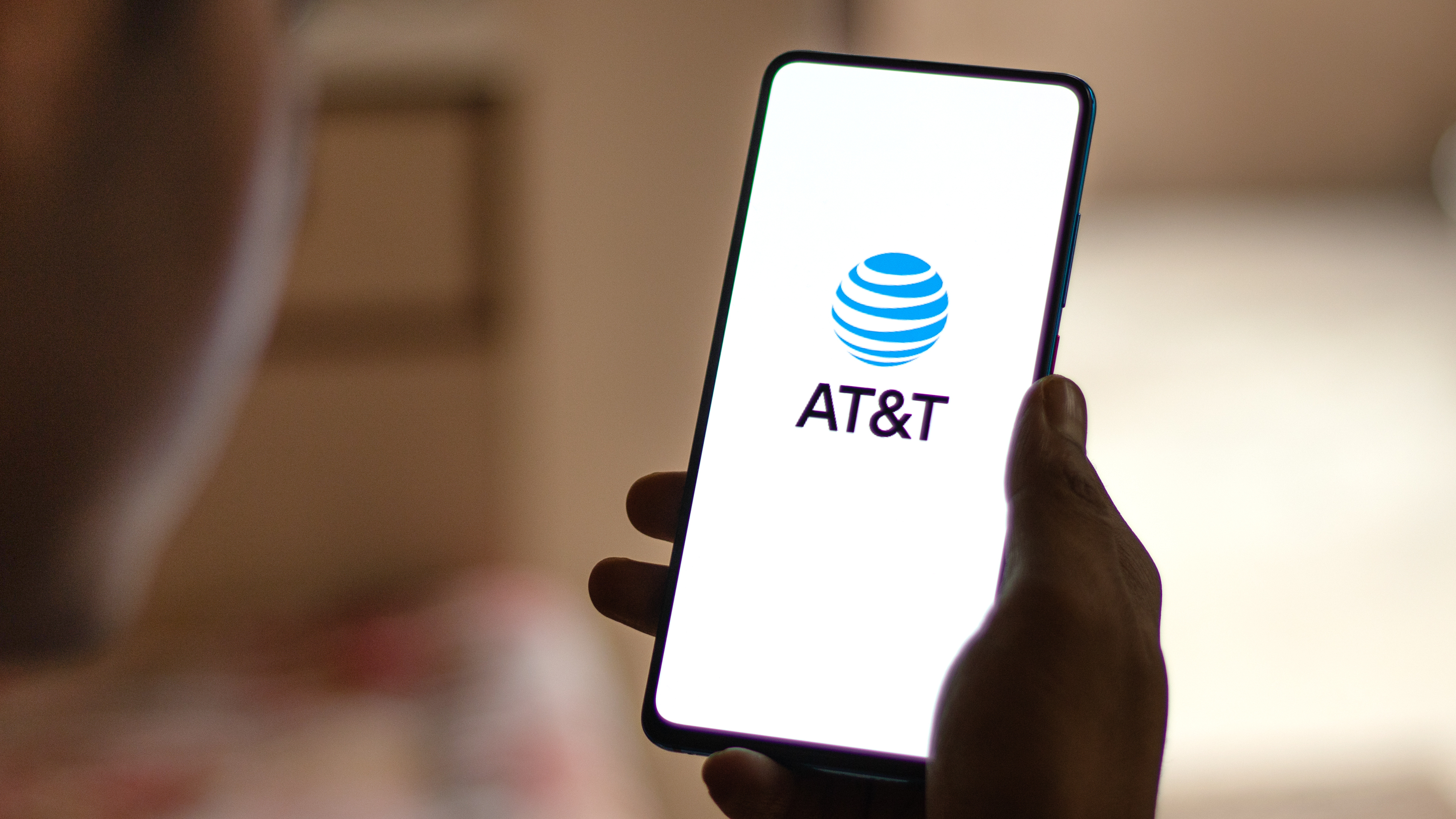 A smartphone being held, with the AT&T logo being displayed on its screen