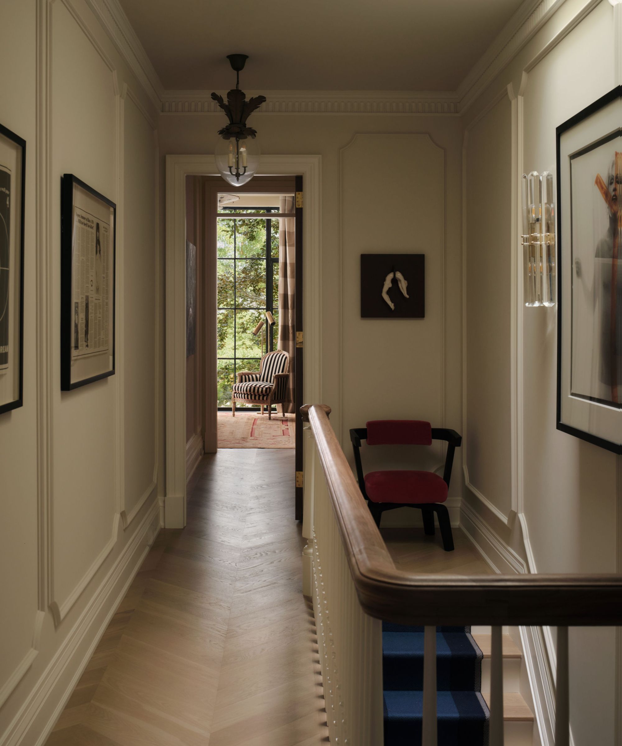 an ornate upstairs landing with paneled walls, an egg light and various eclectic pieces of art