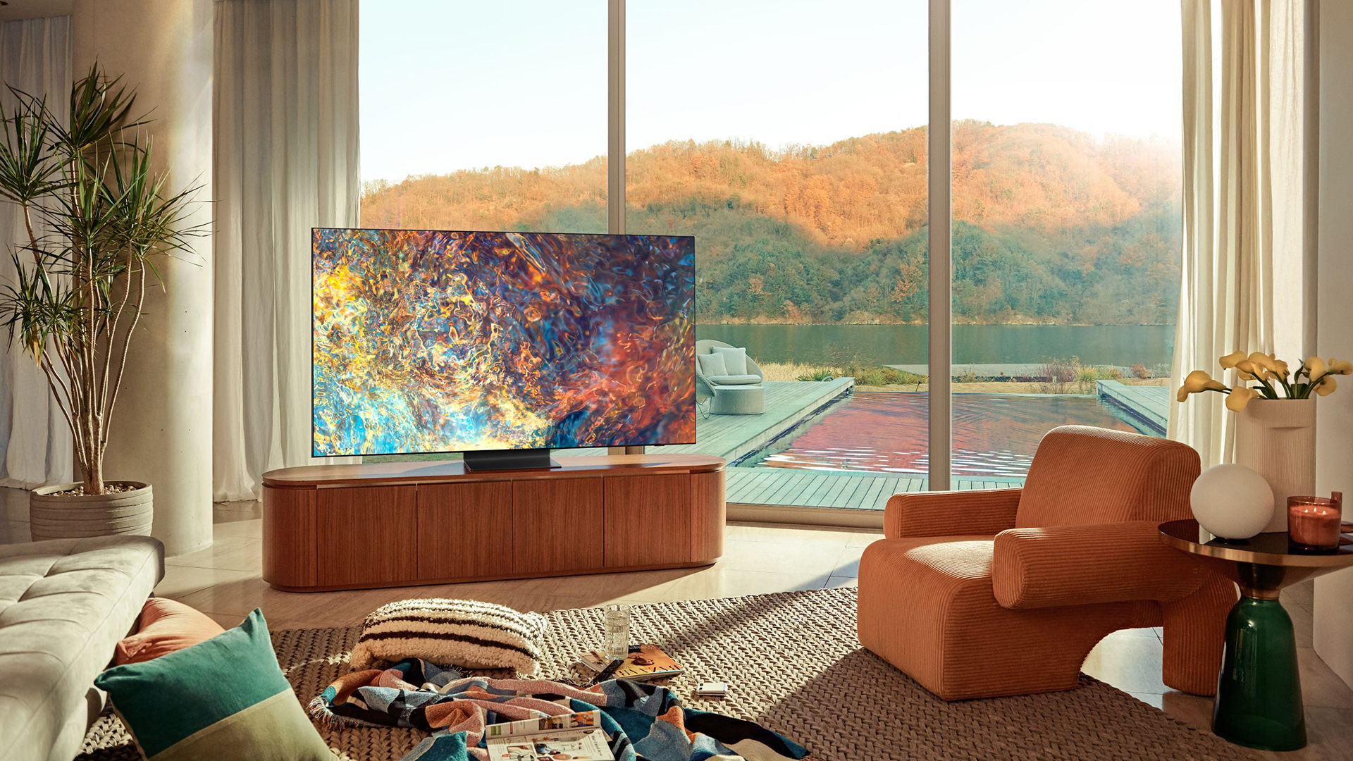 The Samsung QN900A shows colorful display in front of chair and sofa