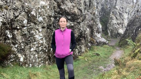 Woman hiking amongst rocks wearing purple vest