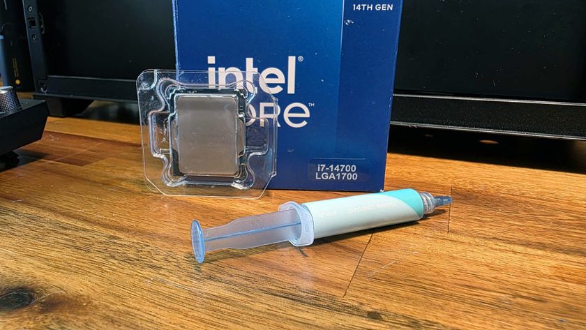 An Intel Core i7-14700 CPU box, along with a cleaned-off version of the Core i5-13500 that was inside, next to a syringe of thermal paste