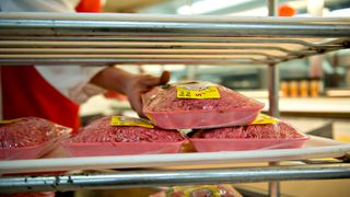 Person stocks packages of ground beef at supermarket