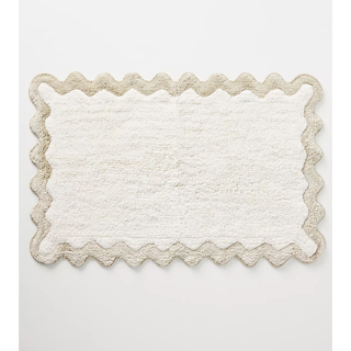 cream bath mat with a beige scalloped edge