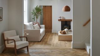 wooden flooring laid in neutral toned hallway leading into living room with hallway laid in herringbone, living room as horizontal planks