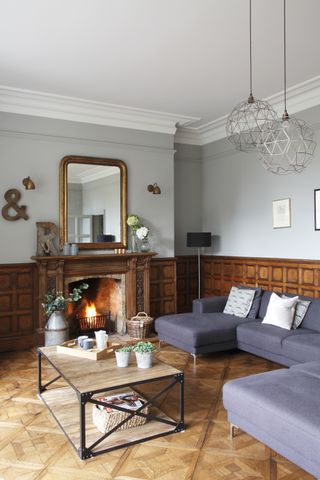 Traditional wooden wall paneling in a living room with eggplant couch and wooden coffee table