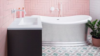 Dark green metro tiles arranged in herringbone pattern on wall of bathroom 
