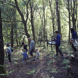 kids and adults in woods carrying chair