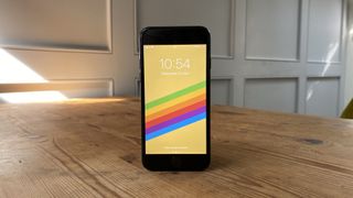 The iPhone SE standing up on a wooden surface