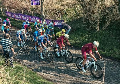 Pro cyclists riding up a cobbled hill